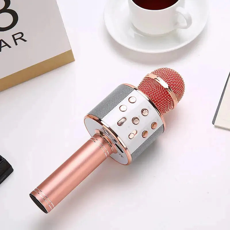 Portable rose gold wireless karaoke microphone with white control panel, integrated Bluetooth speaker, and multi-function buttons.