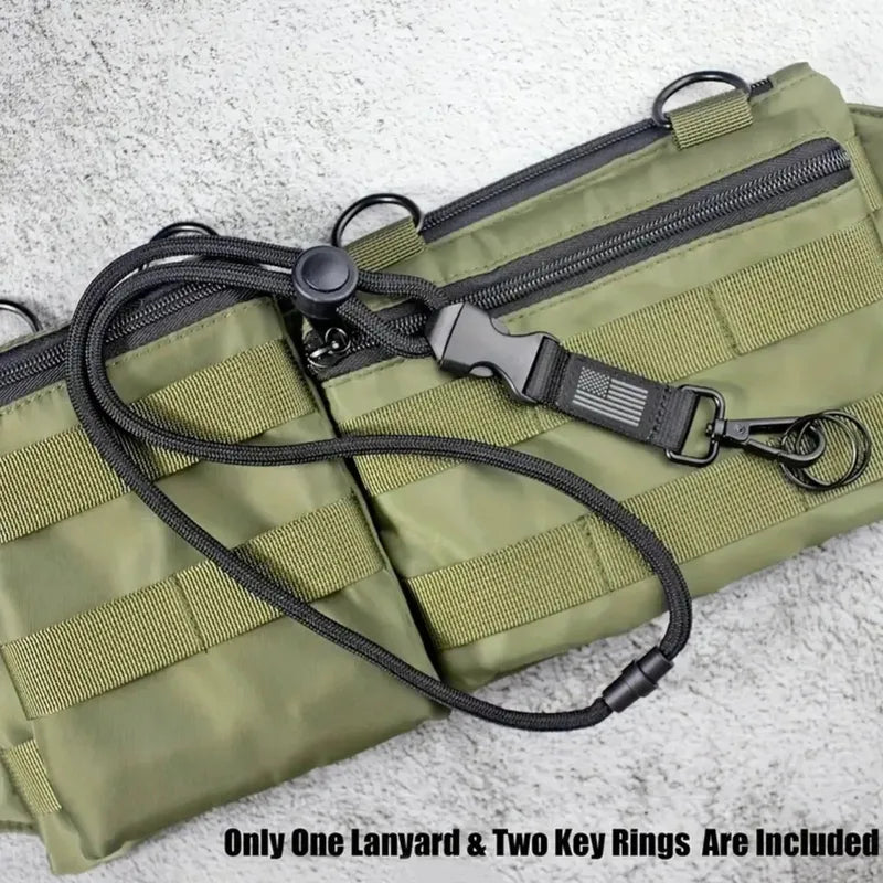 Black heavy-duty braided polyester lanyard with quick-release buckle, metal clip, and US flag detail, on an olive green tactical bag.
