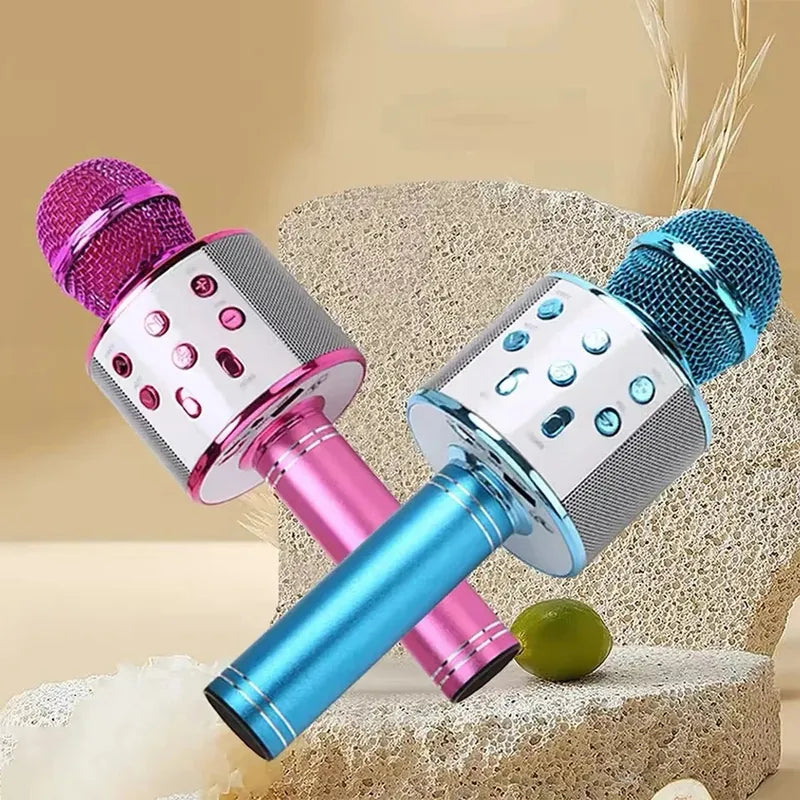 Pink and blue wireless karaoke microphones with white control panels, silver speaker grills, and metallic handles.