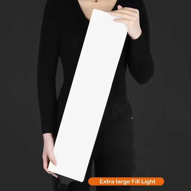 Person holding a large white rectangular LED fill light for dimmable continuous photography.