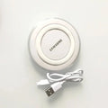 White Samsung Qi wireless charging pad, circular design with clear edge, shown with its coiled micro USB cable.